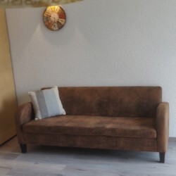 Ein Bild, das ein braunes Sofa vor einer Wand zeigt.