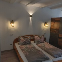 Ein Bild, das ein Doppelbett neben einem Schrank zeigt.