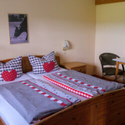 Schlafzimmer Schlafzimmer mit Doppelbett und kleinem Tisch aus Holz, mit hellgelber Wandfarbe.