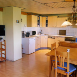 Wohnküche Wohnküche mit Holz-Esstisch mit Eckbank und Küchenzeile.