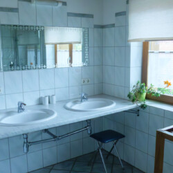 Bad Gefließtes Badezimmer mit zwei Waschbecken und Spiegel.